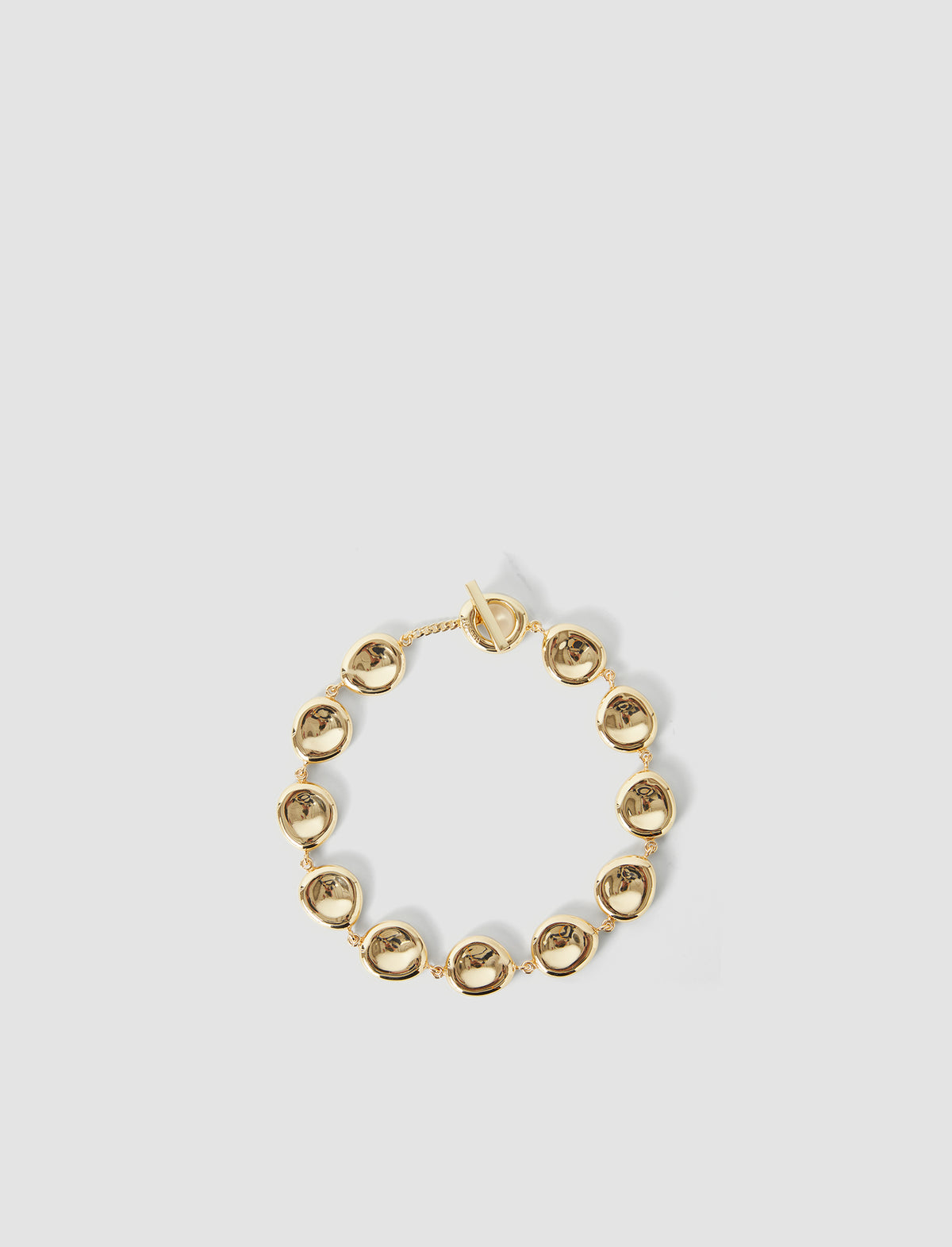 Gold bracelet on a light gray background