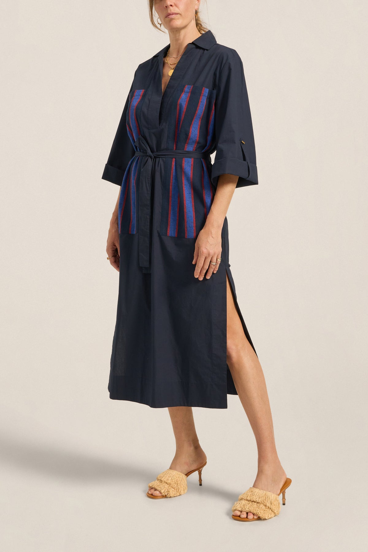 Woman wearing a navy dress with a striped pattern on a beige background