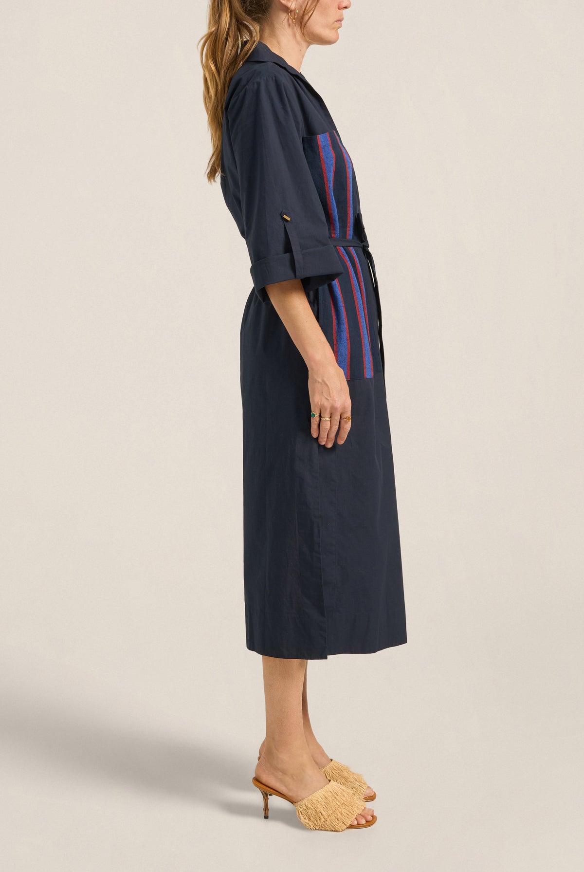 Woman wearing a navy dress with a striped pattern on a beige background