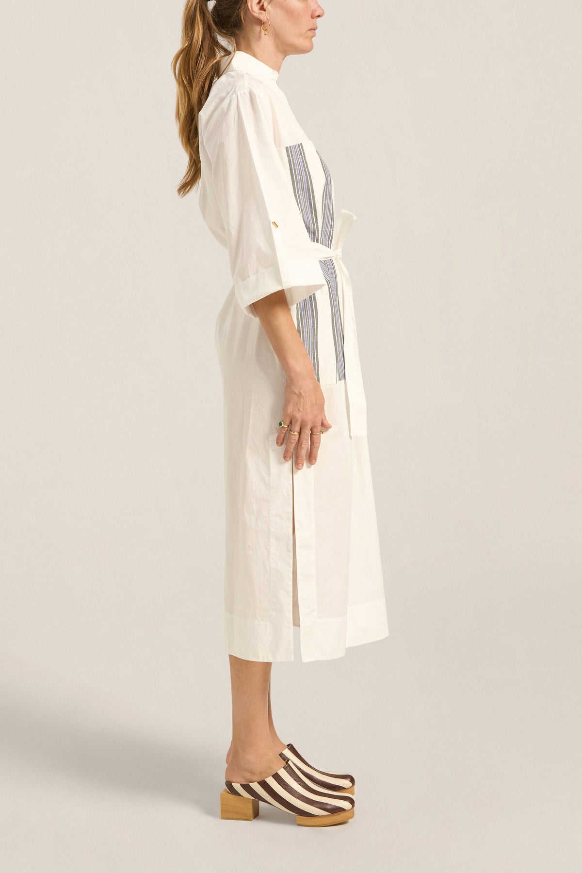 Woman wearing a white dress with a gray pattern on a plain background