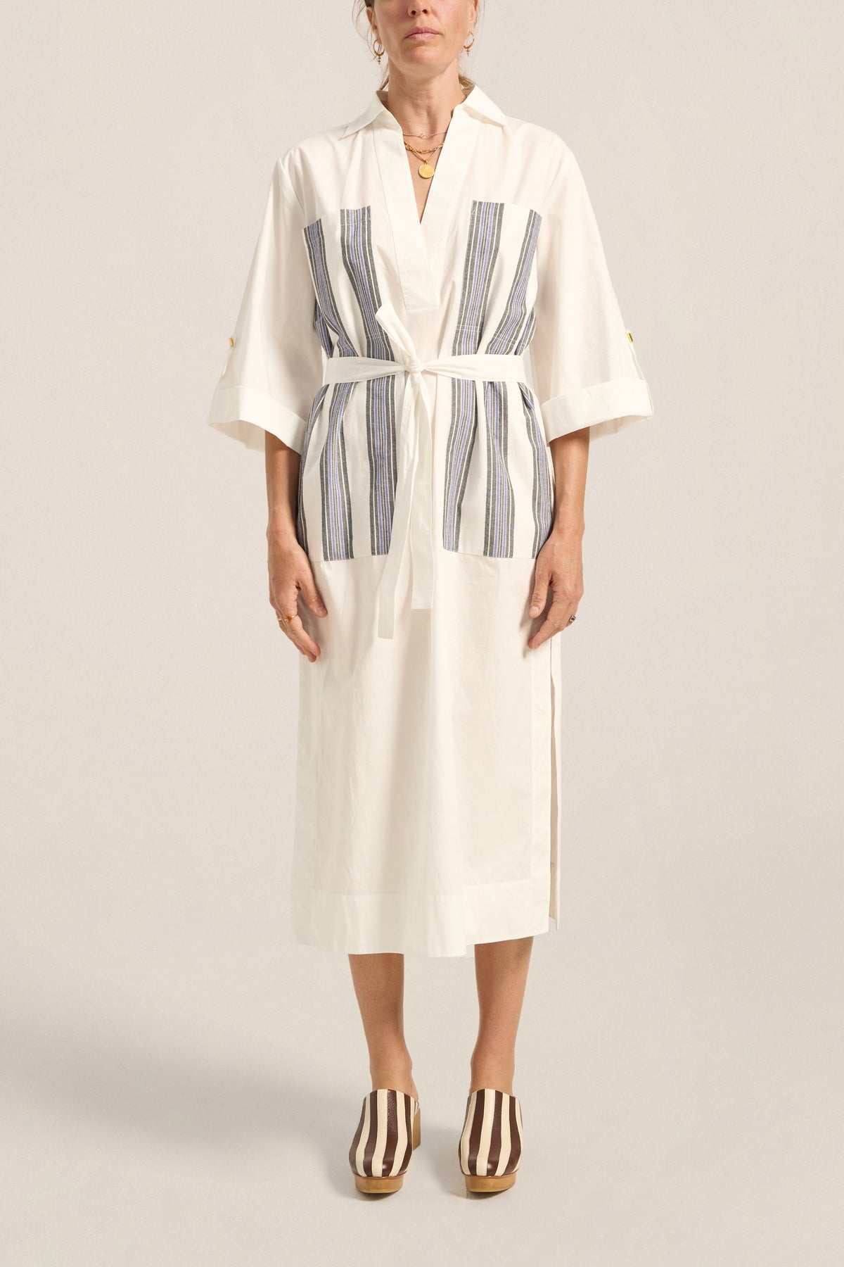 Woman wearing a white robe with blue stripes on a plain background