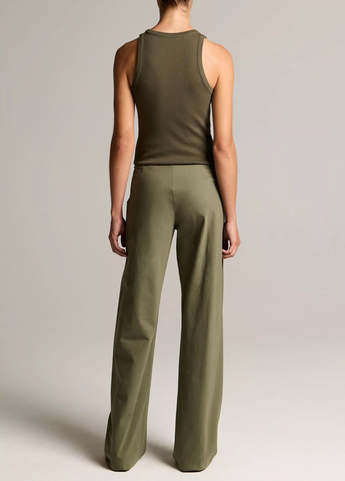 Person wearing a green tank top and wide-leg pants on a plain background