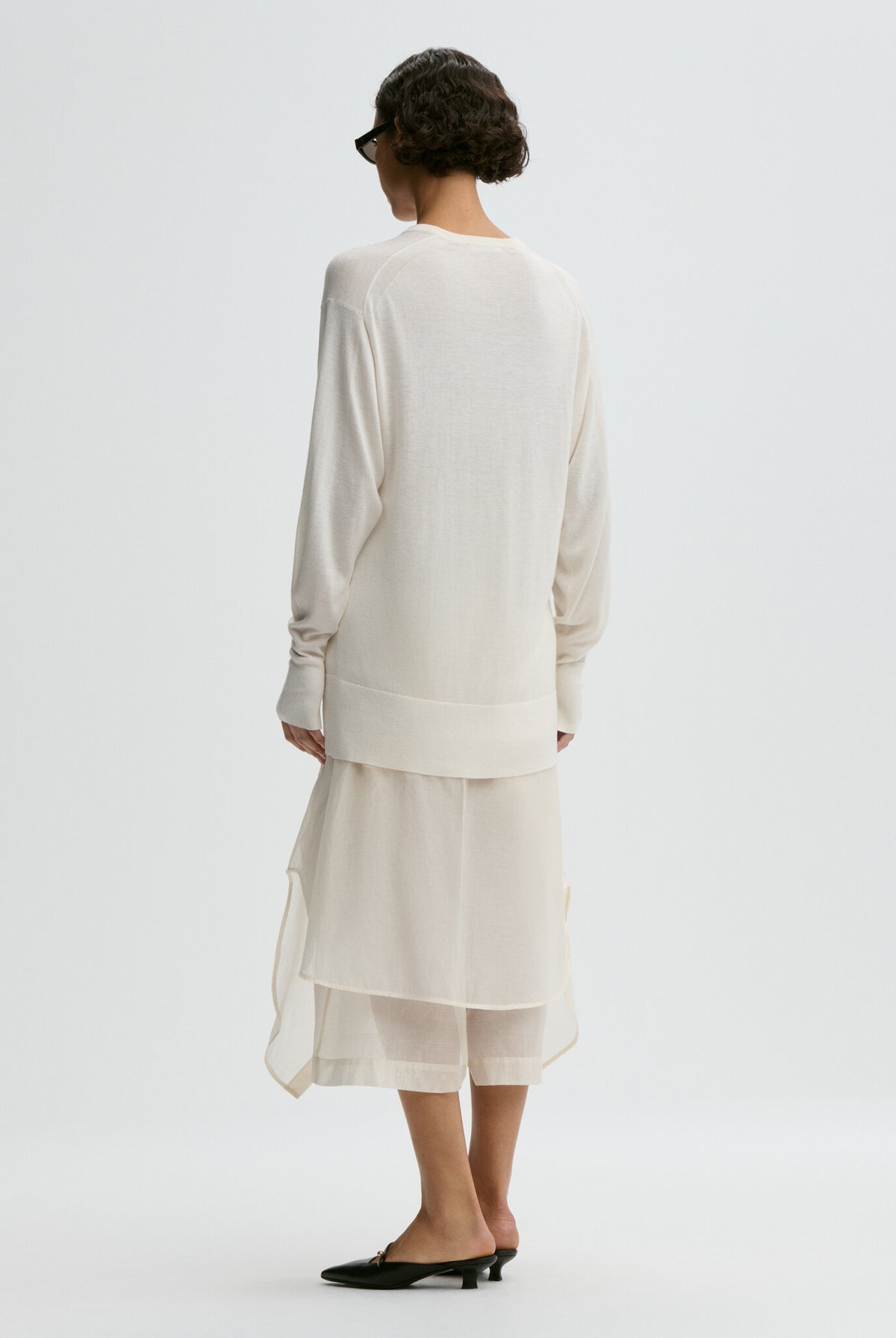 Woman wearing a white outfit on a plain background