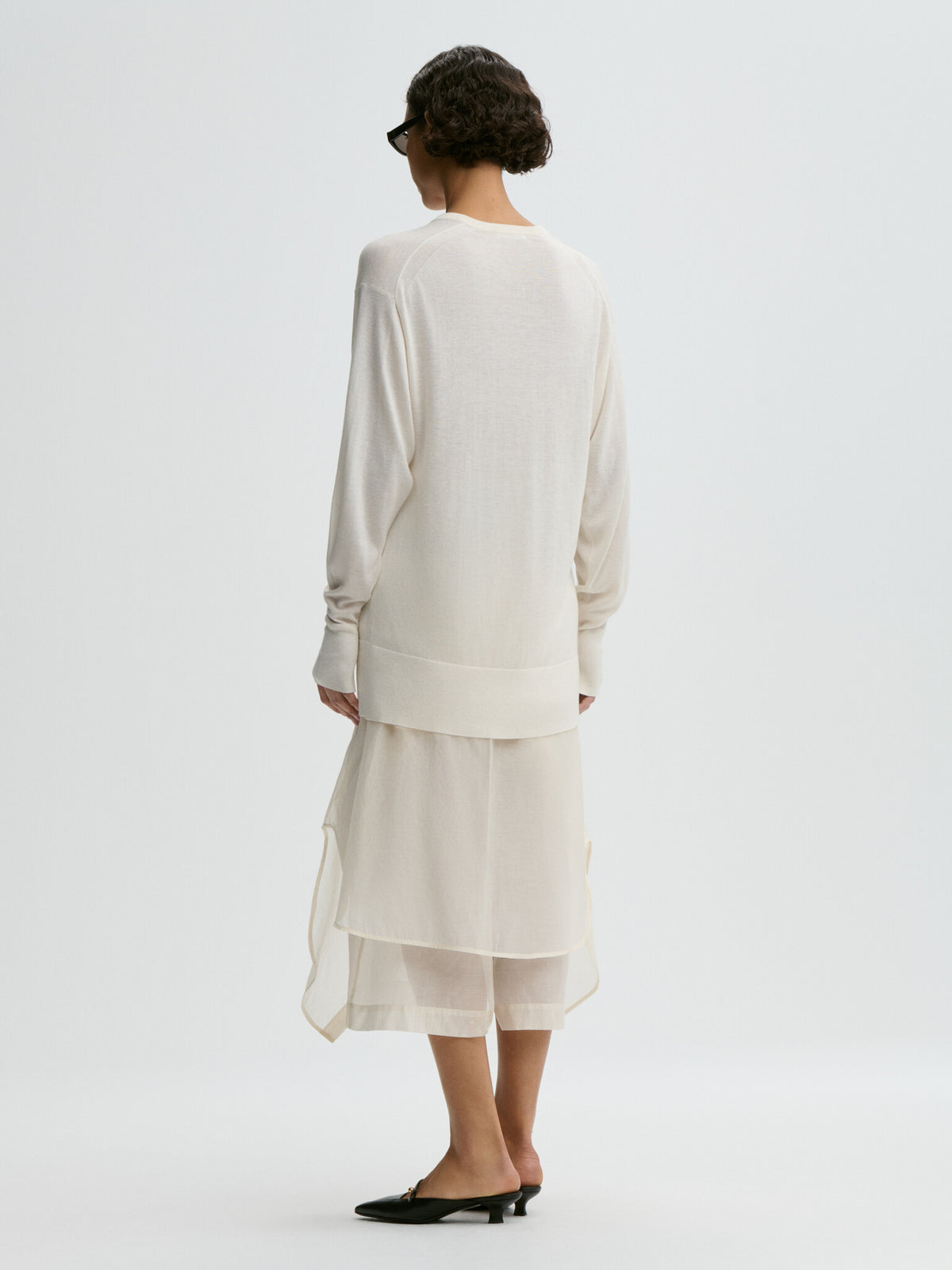 Woman wearing a white outfit on a plain background