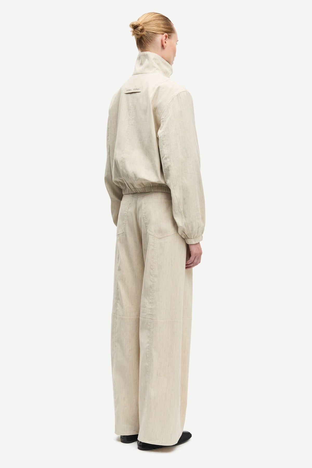 Person wearing a beige jumpsuit on a white background
