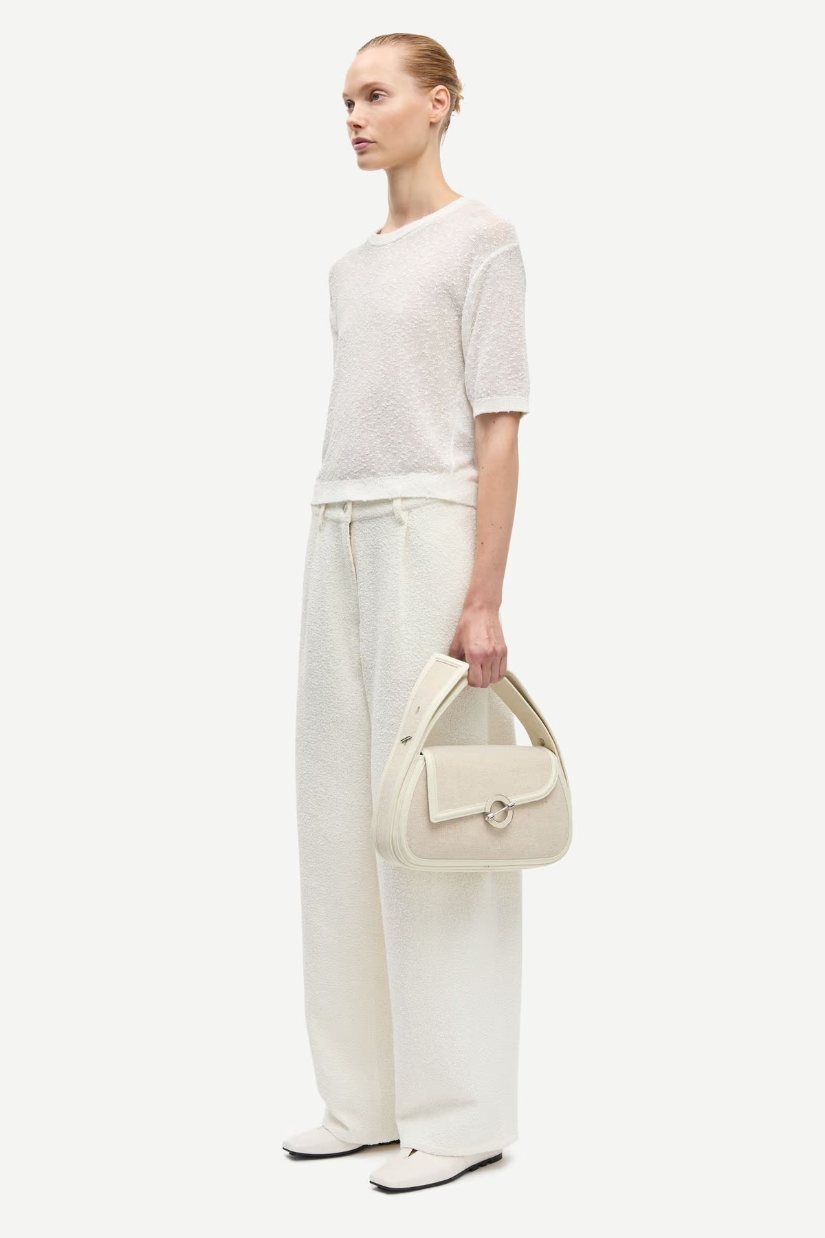 Woman holding a cream handbag against a white background