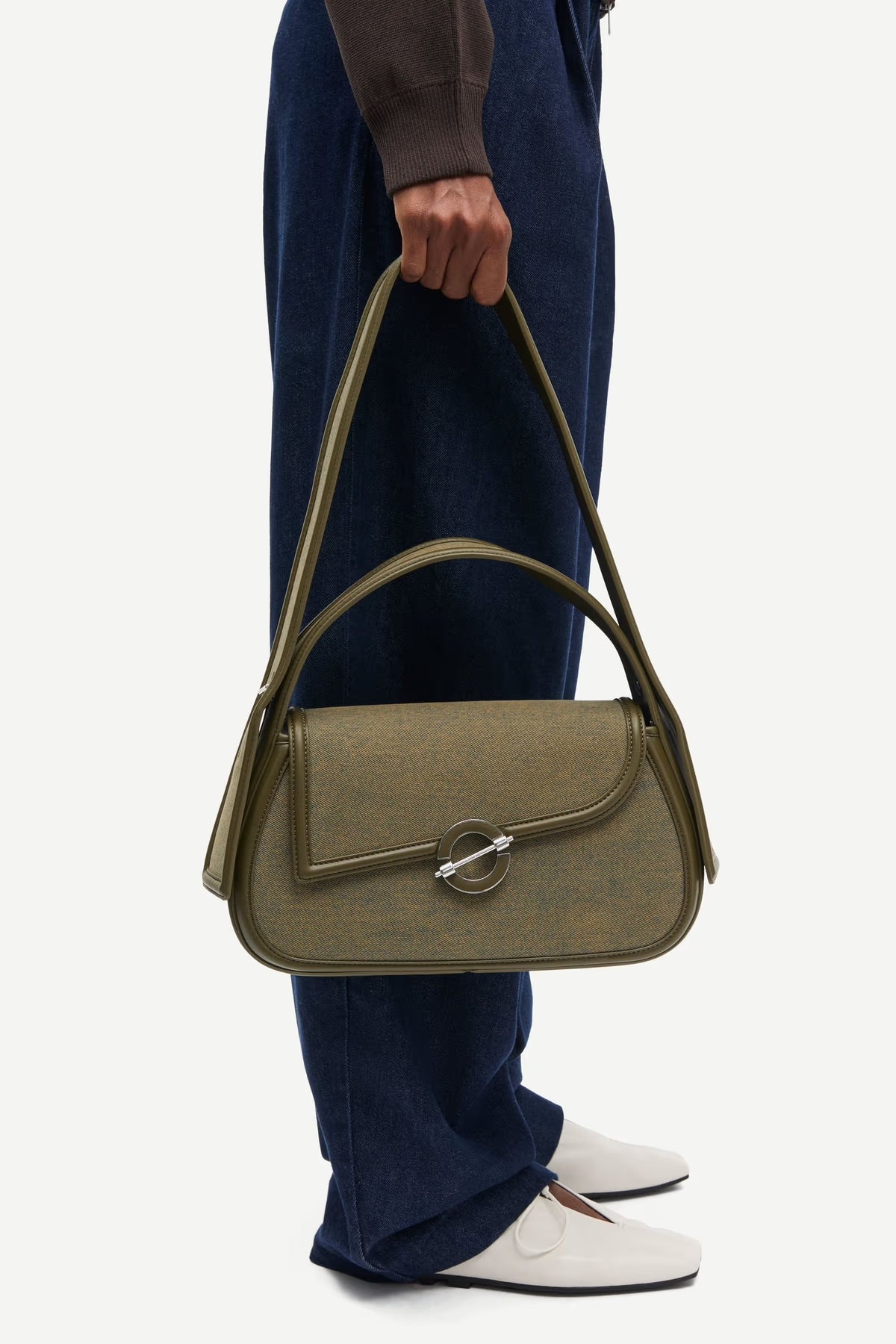 Person holding a green handbag with a plain background