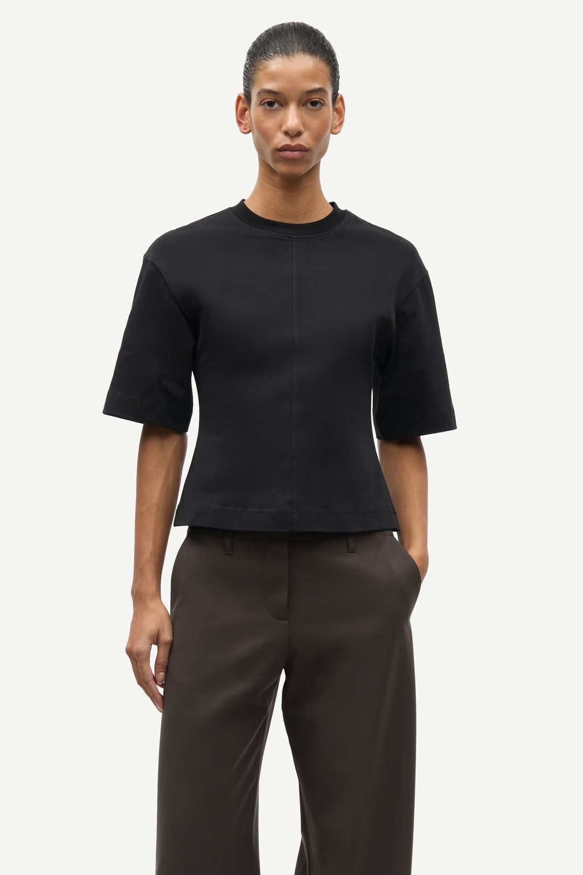 Person wearing a black t-shirt and dark pants on a white background