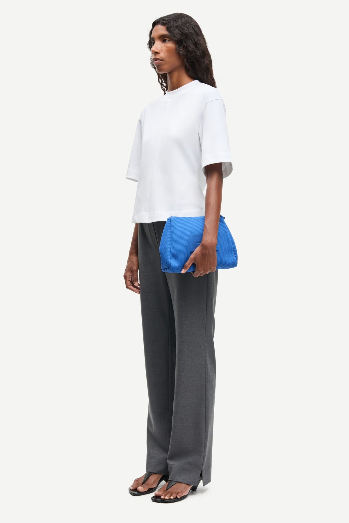 Woman holding a blue clutch bag against a white background