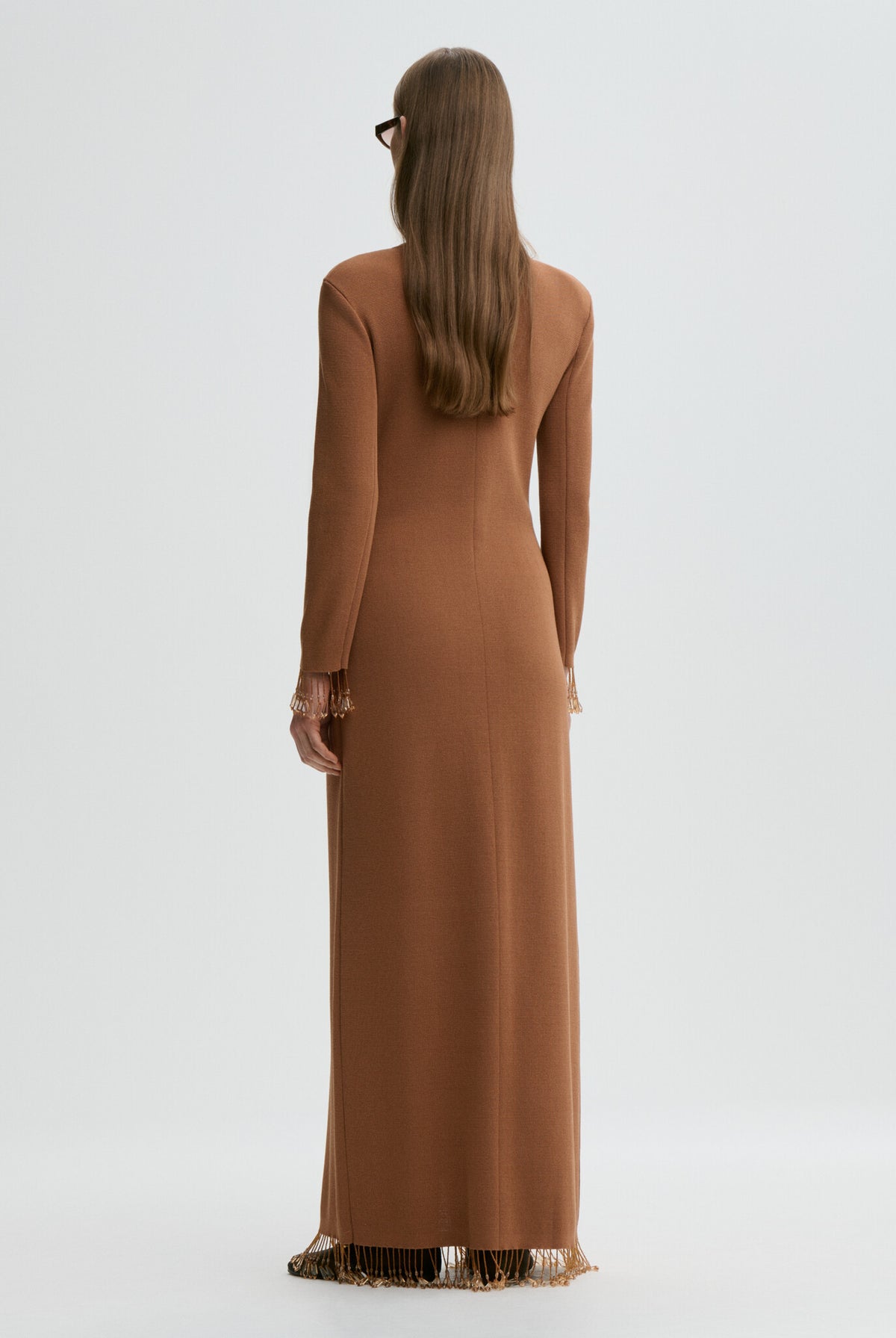 Woman wearing a long brown dress with a plain background
