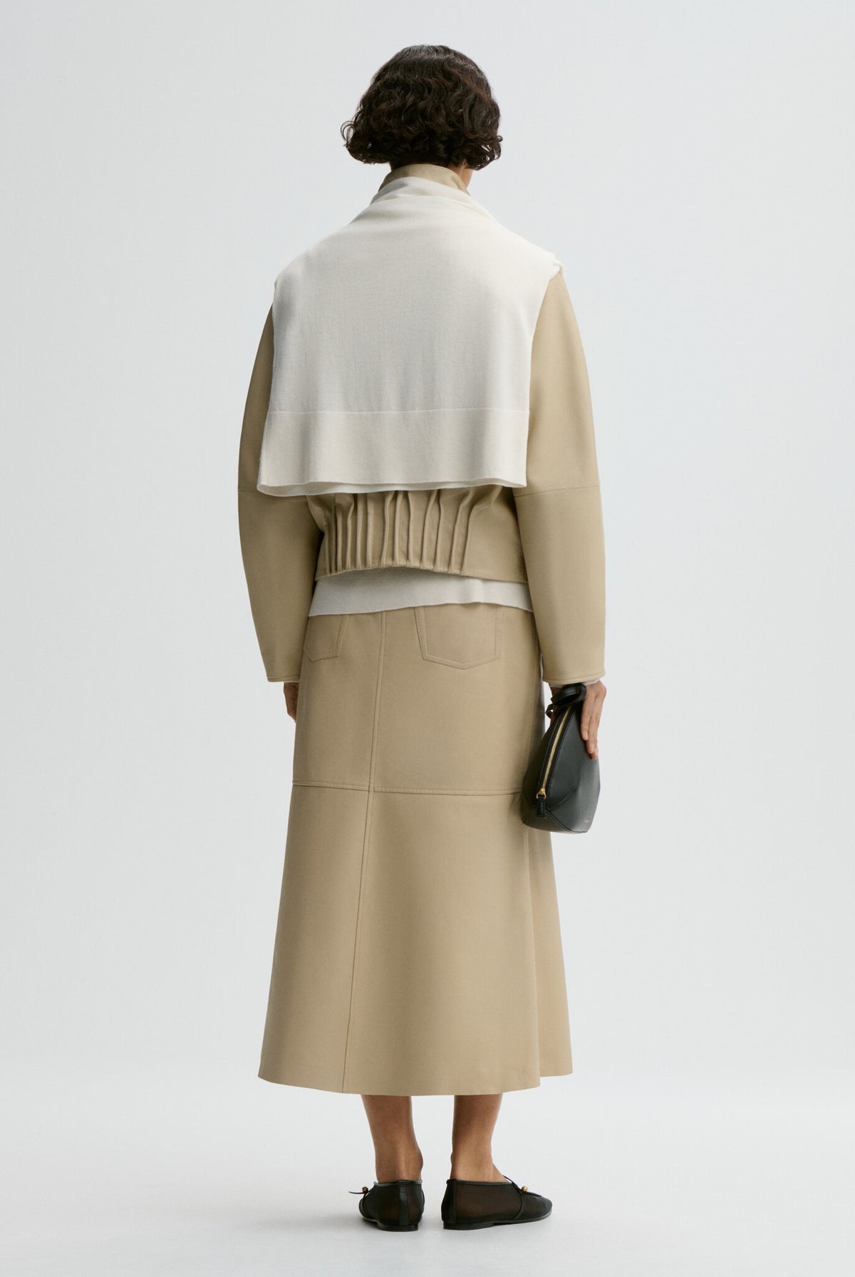 Person wearing a beige jacket and skirt set on a white background