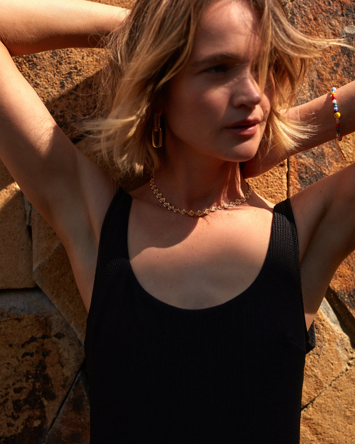 Woman in a black dress standing against a stone wall