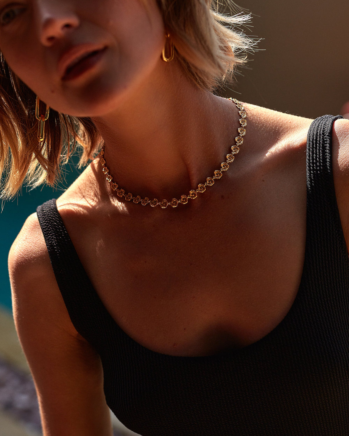 Woman wearing a gold necklace with a blurred background