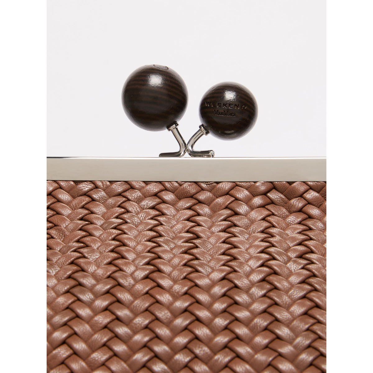 Close-up of a woven clutch bag with wooden clasp on a white background