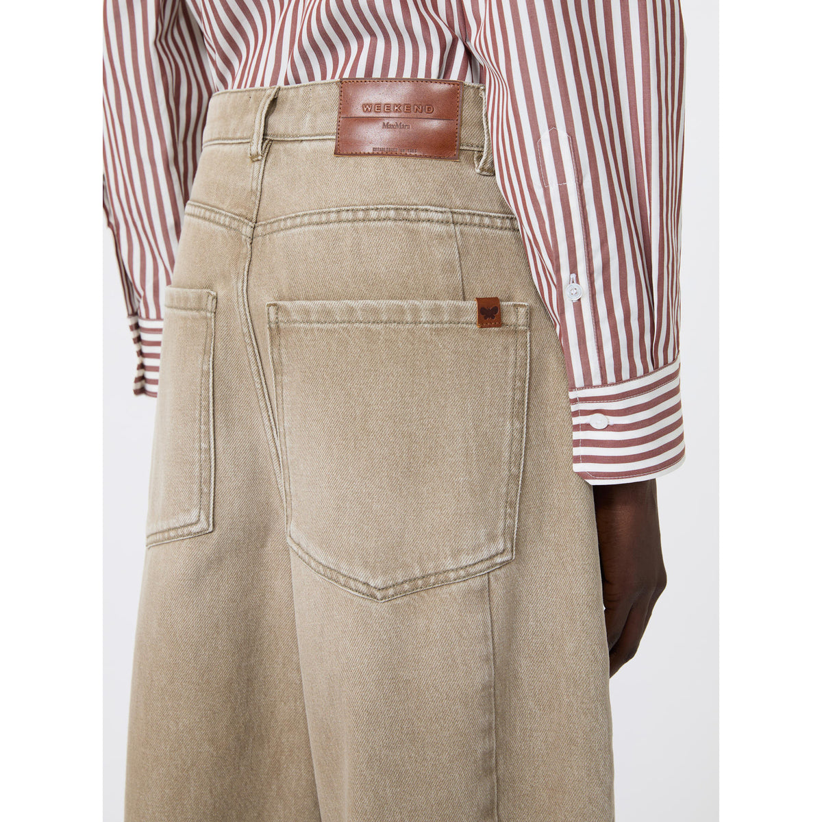 Beige pants with a brown leather belt and red and white striped shirt on a white background