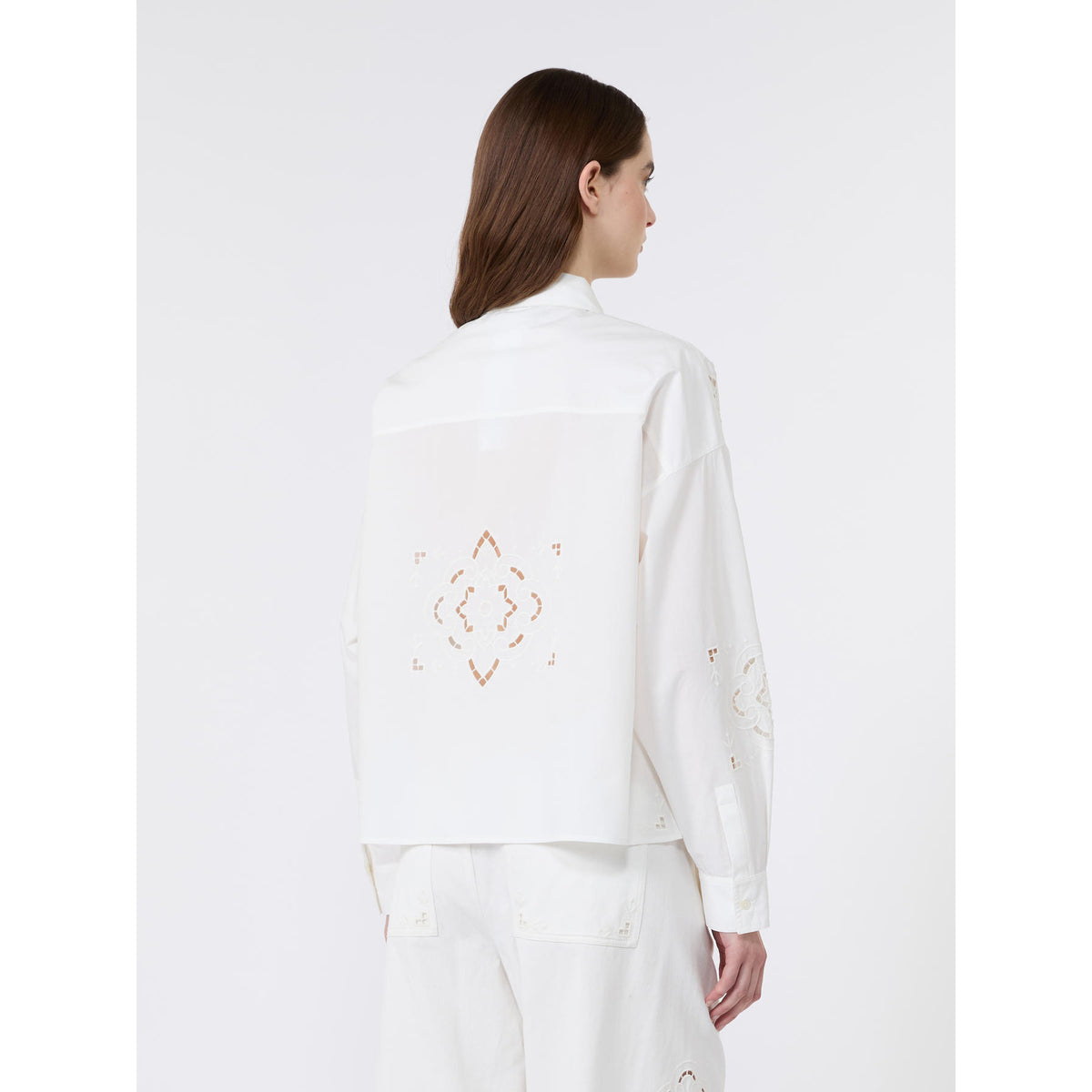 Woman wearing a white blouse with embroidery on a white background