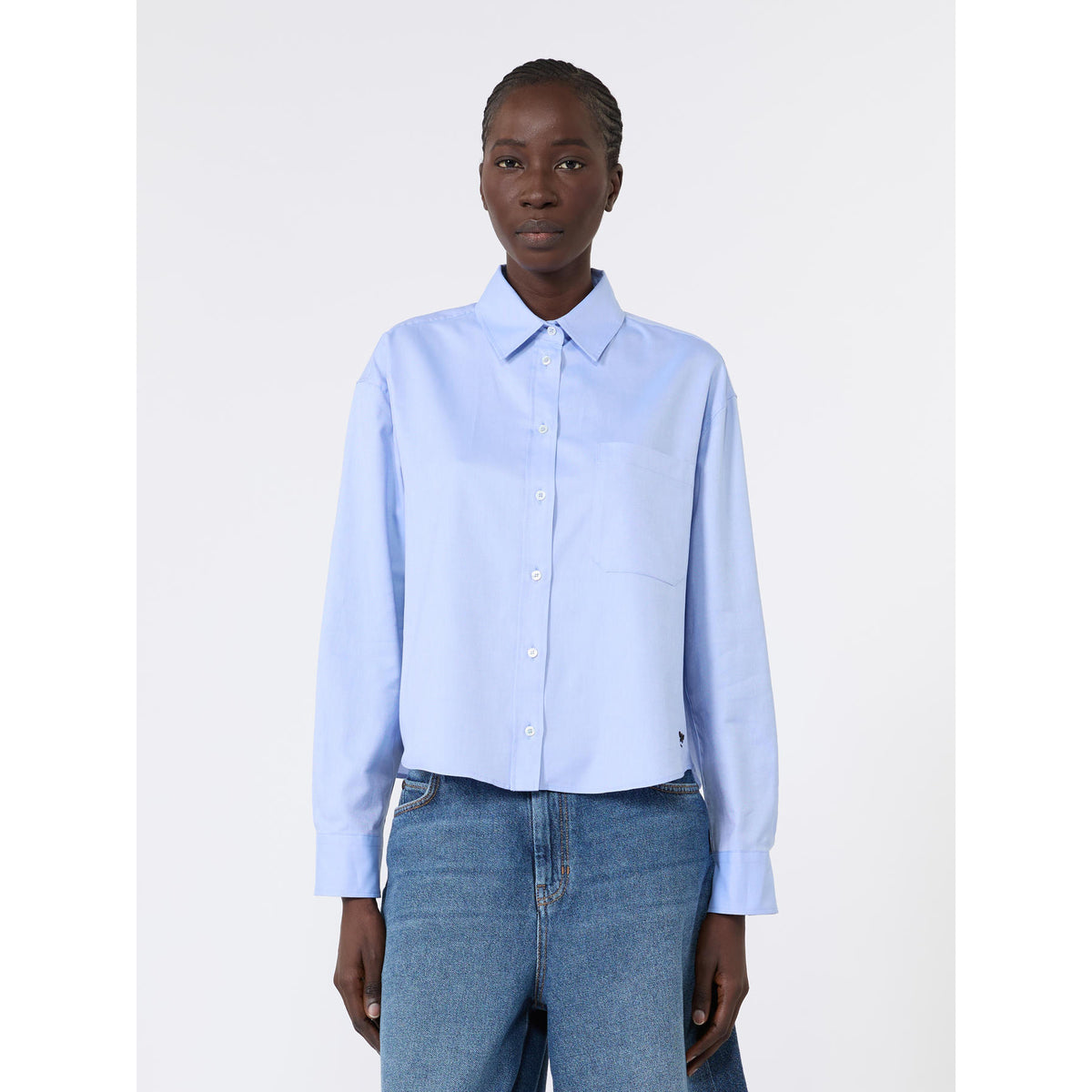 Person wearing a light blue shirt and jeans on a white background