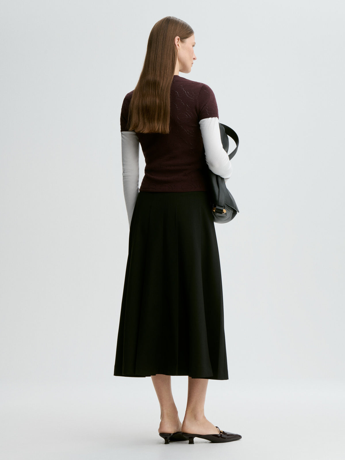 Woman wearing a dark top and black skirt with a white background
