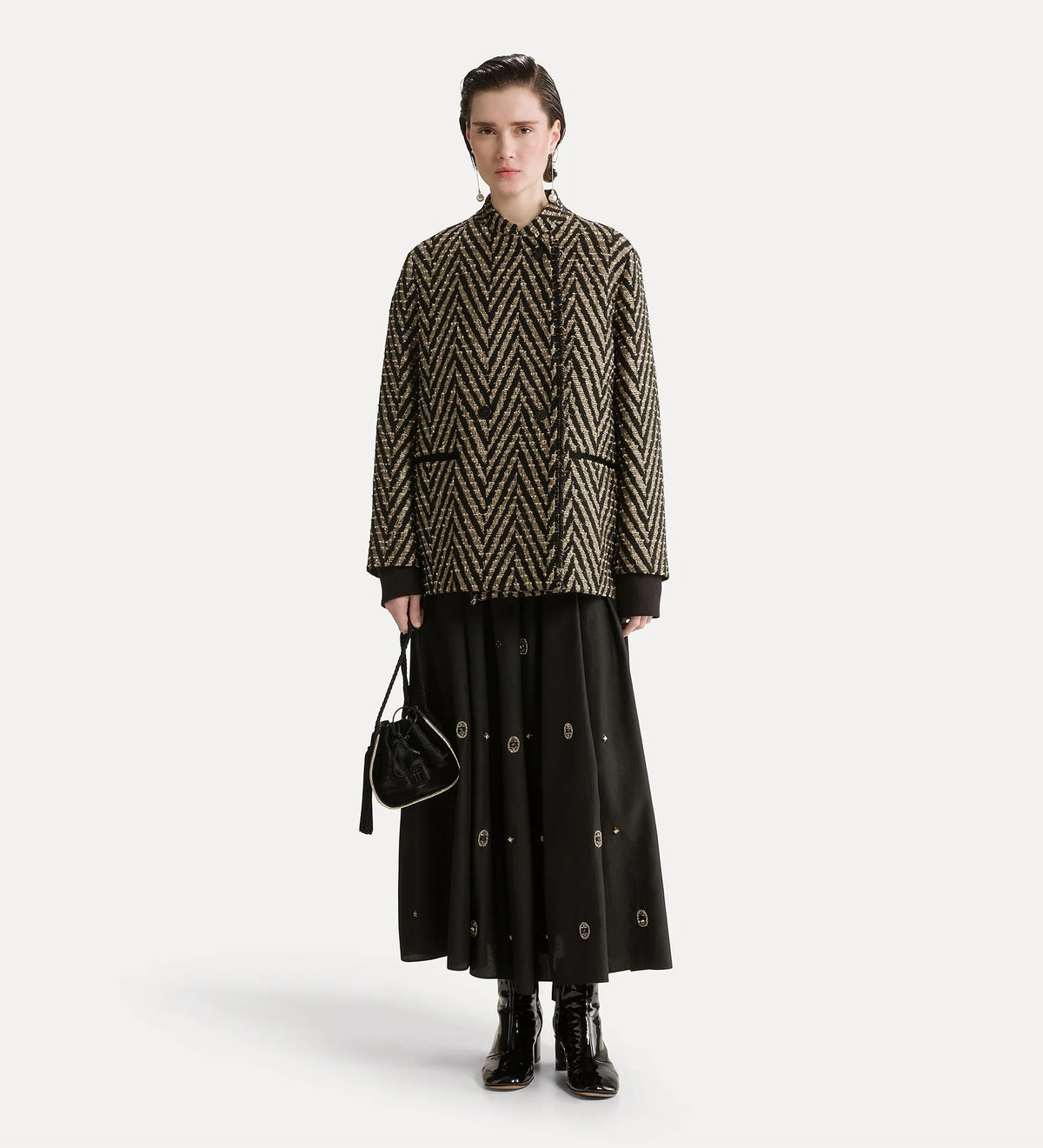 Person wearing a patterned jacket and black skirt on a white background