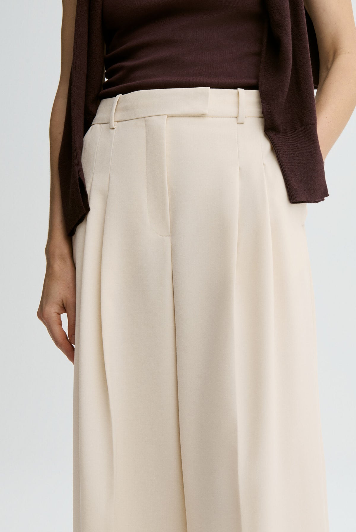 Person wearing a brown top and beige wide-leg pants on a light gray background