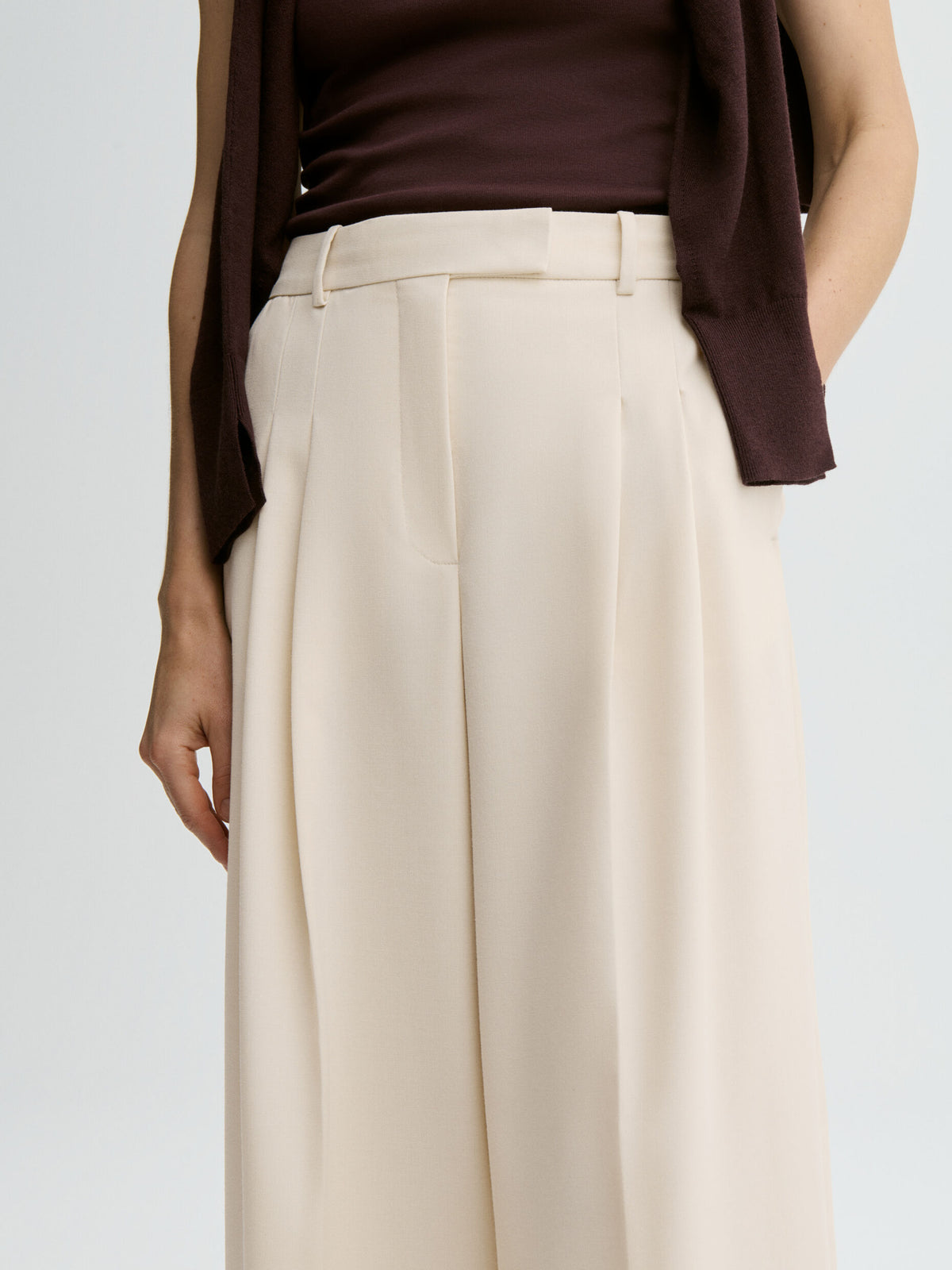 Person wearing a brown top and beige wide-leg pants on a light gray background