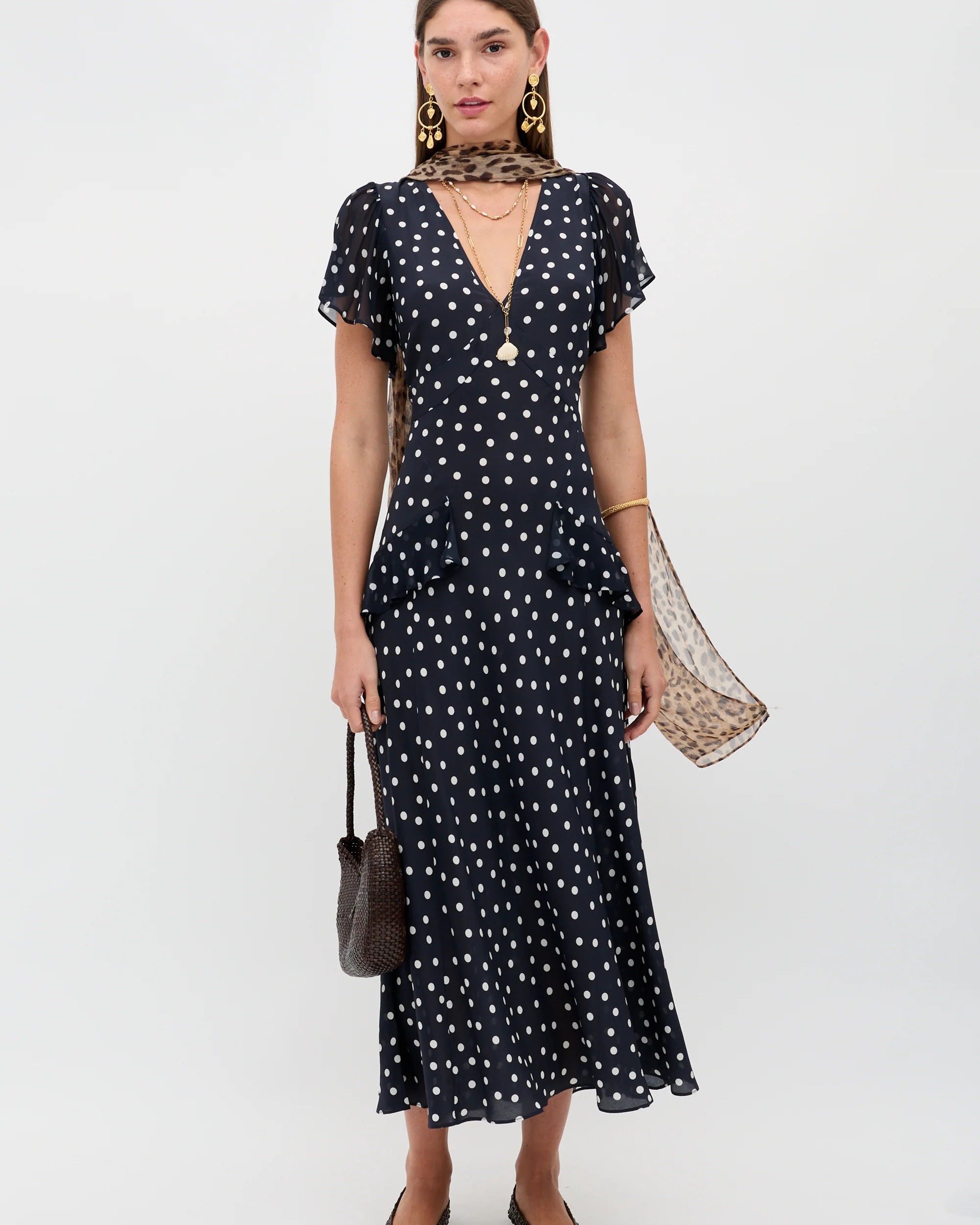 Woman wearing a black dress with white polka dots on a white background