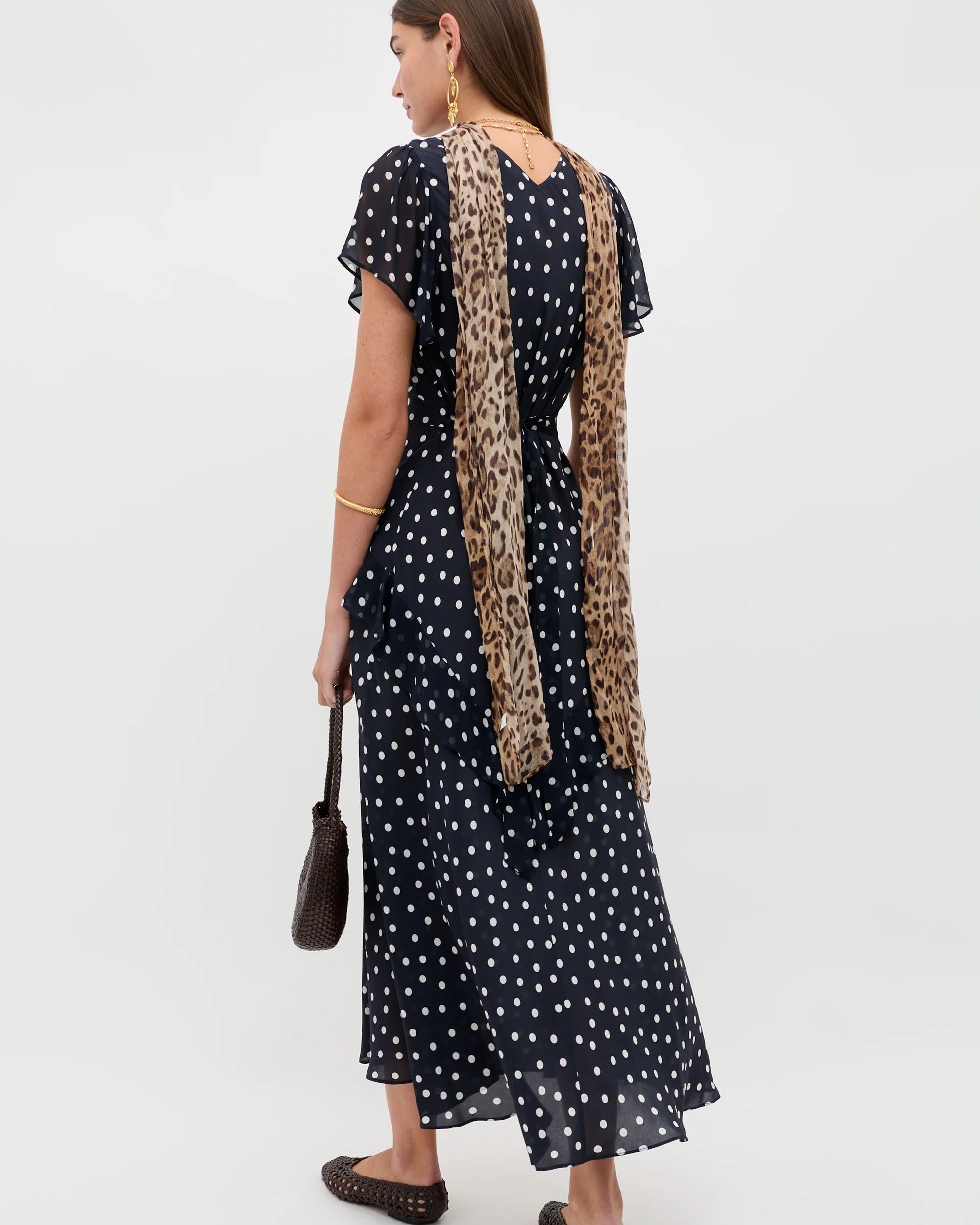 Woman wearing a black polka dot dress with a leopard print scarf on a white background