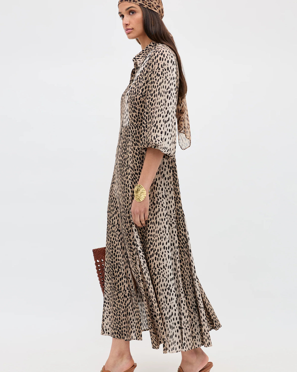 Woman wearing a leopard print dress and headscarf on a white background