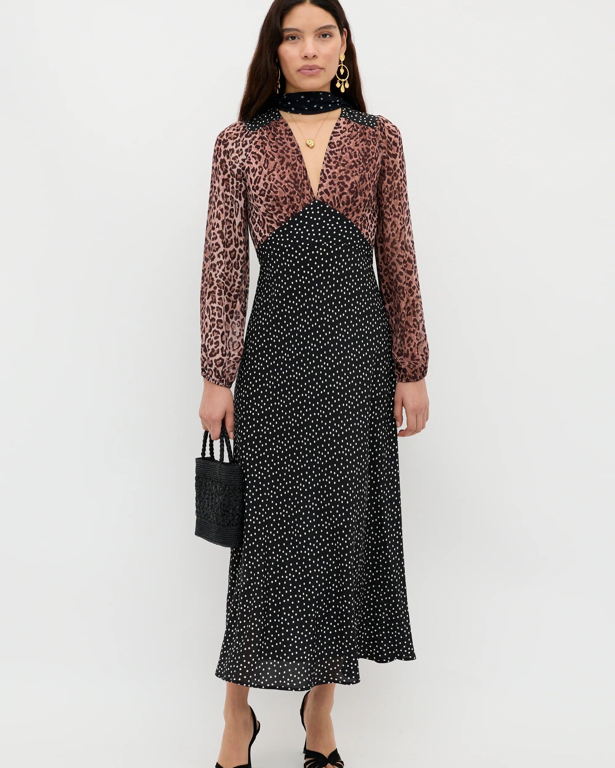 Woman wearing a black and white patterned dress with a sheer brown top on a white background