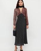 Woman wearing a black and white patterned dress with a sheer brown top on a white background