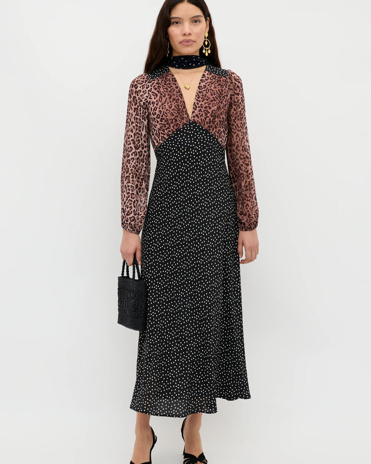 Woman wearing a black and white patterned dress with a sheer brown top on a white background