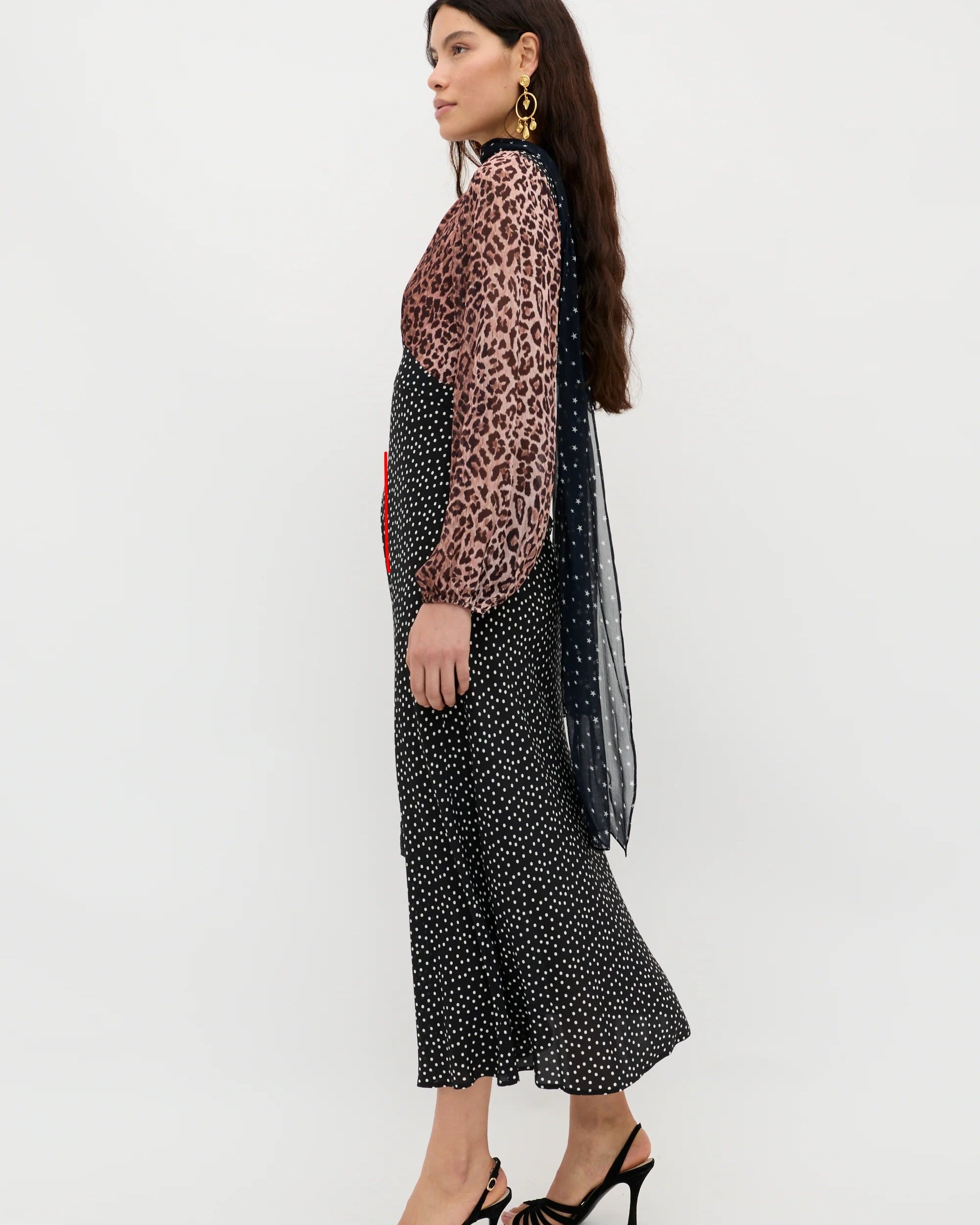 Woman wearing a leopard print top and black patterned skirt on a white background