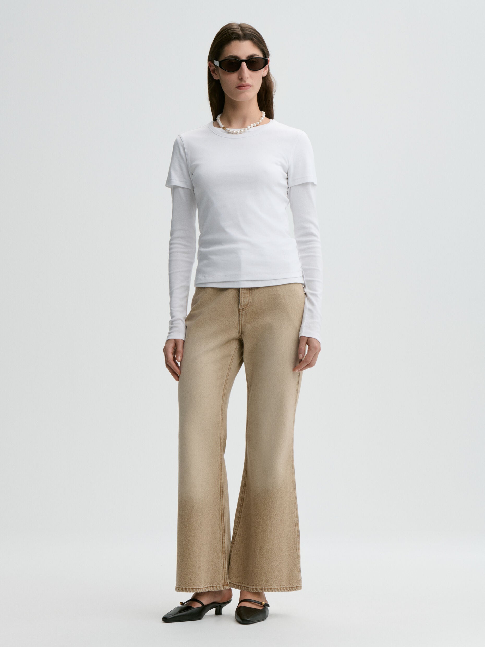 Woman wearing a white top and beige pants on a white background