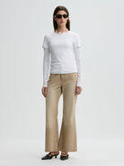 Woman wearing a white top and beige pants on a white background