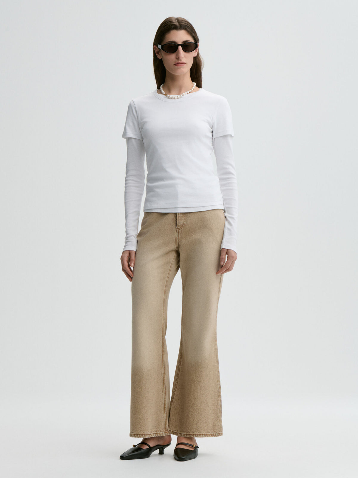 Woman wearing a white top and beige pants on a white background