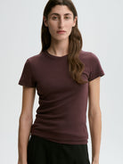 Woman wearing a maroon t-shirt against a plain background