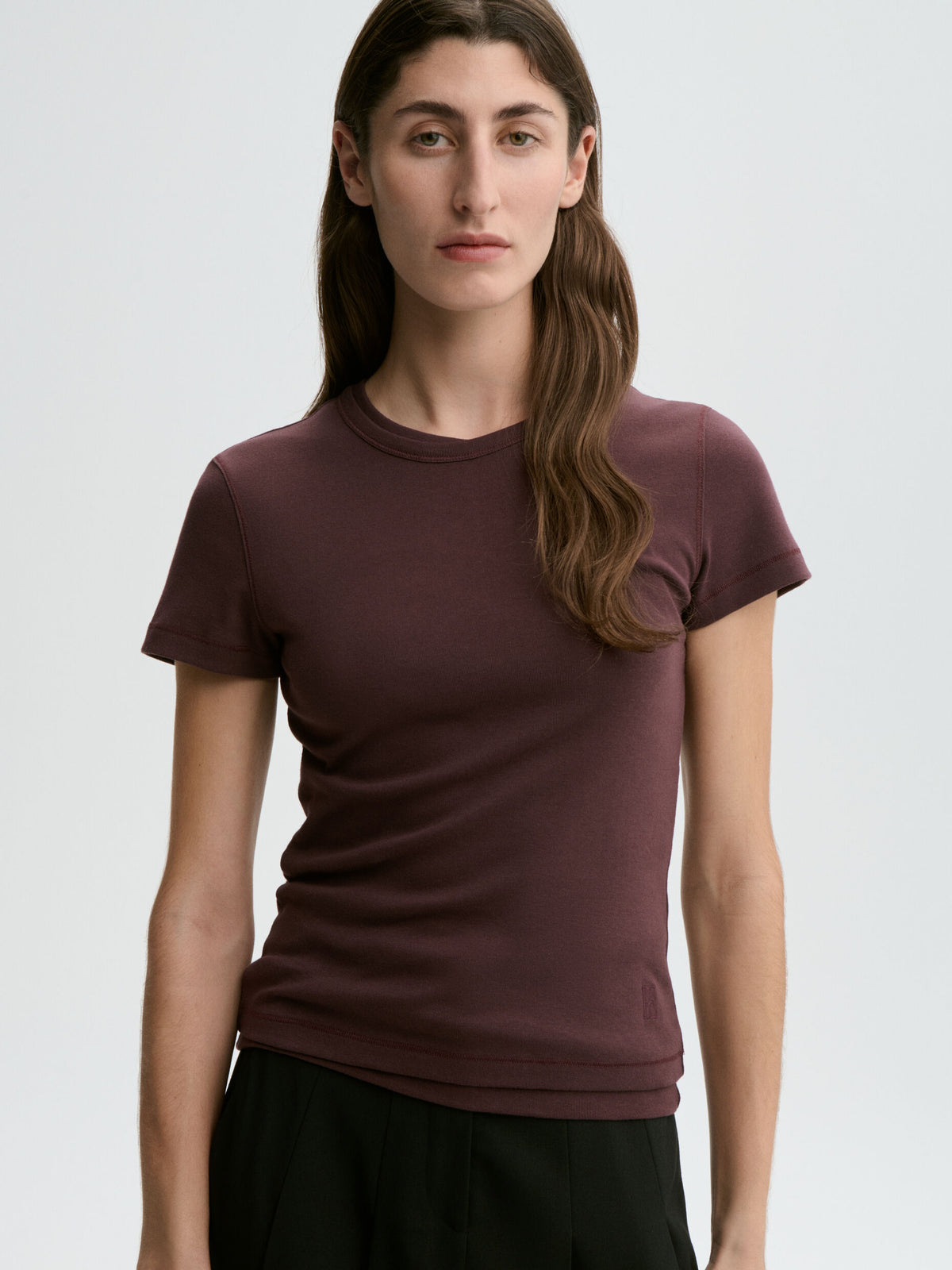 Woman wearing a maroon t-shirt against a plain background