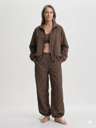 Woman wearing a brown patterned outfit on a white background