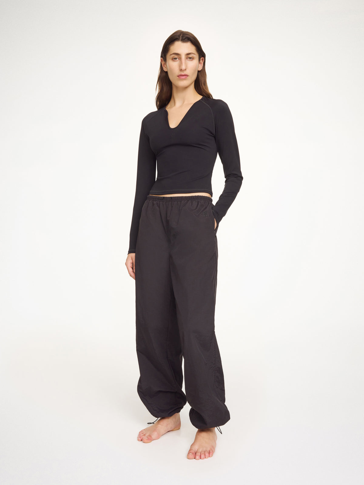 Woman wearing a black long-sleeve top and wide-leg pants on a white background