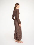 Woman wearing a brown patterned outfit on a white background