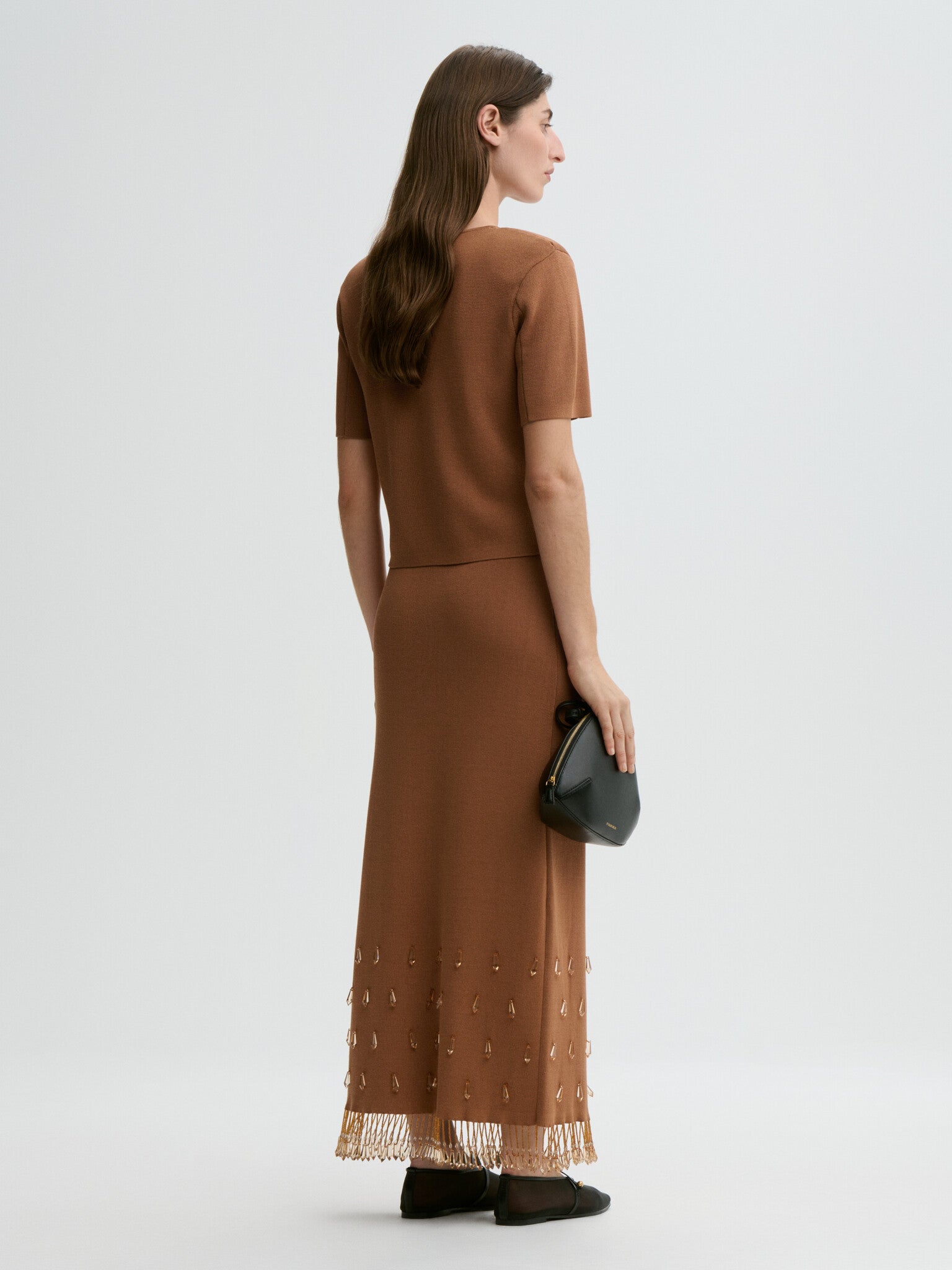 Woman wearing a brown dress with a sheer overlay on a white background