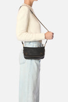 Person wearing a black crossbody bag with a white background