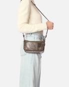 Person wearing a cream sweater and light blue jeans with a brown leather handbag on a white background