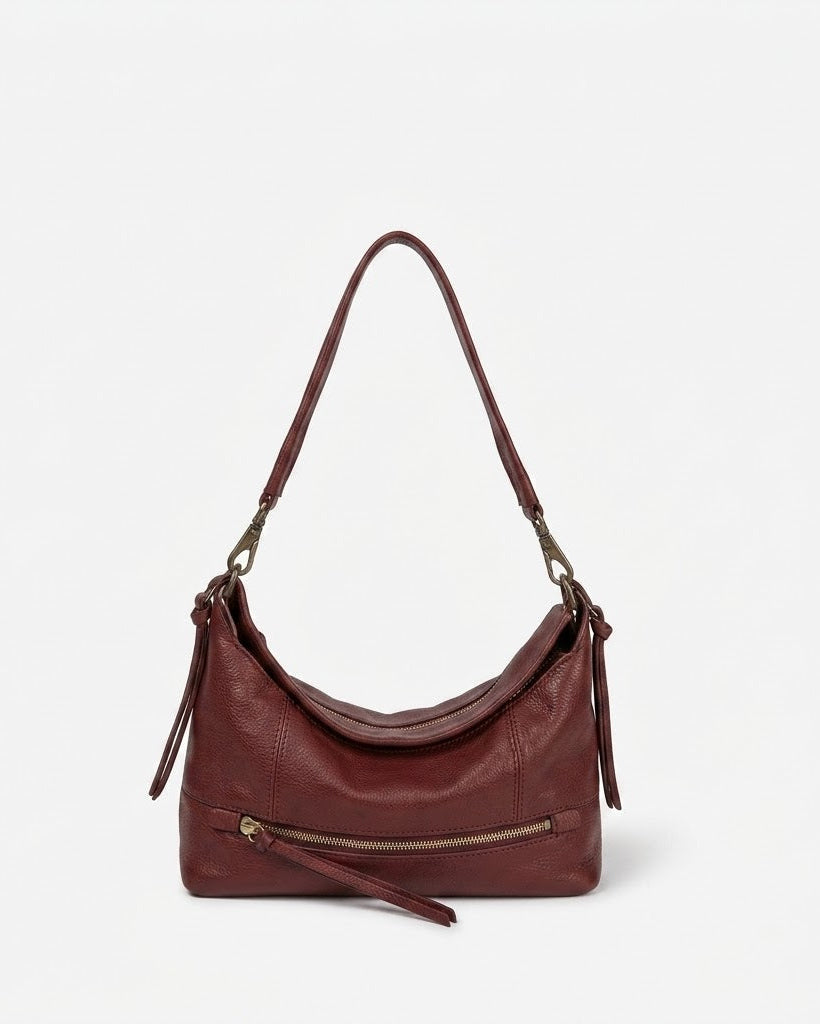 Burgundy leather handbag with a shoulder strap on a light gray background