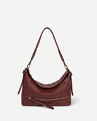 Burgundy leather handbag with a shoulder strap on a light gray background