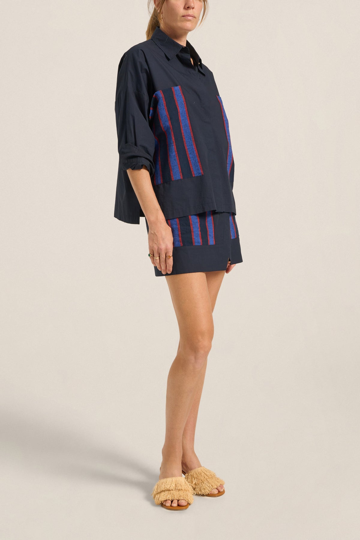 Woman wearing a navy outfit with red and blue striped accents on a beige background