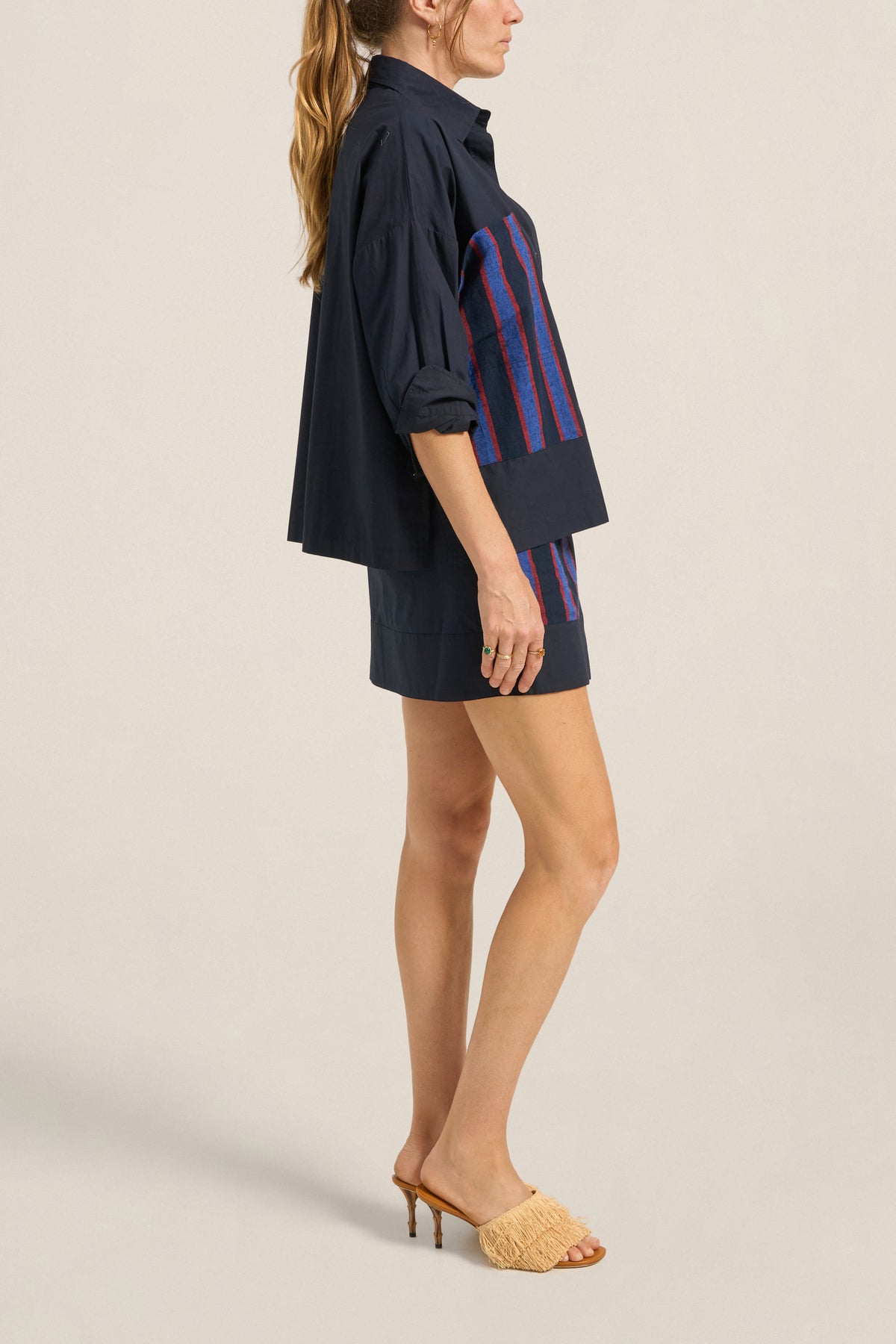 Woman wearing a navy dress with colorful stripes on a beige background