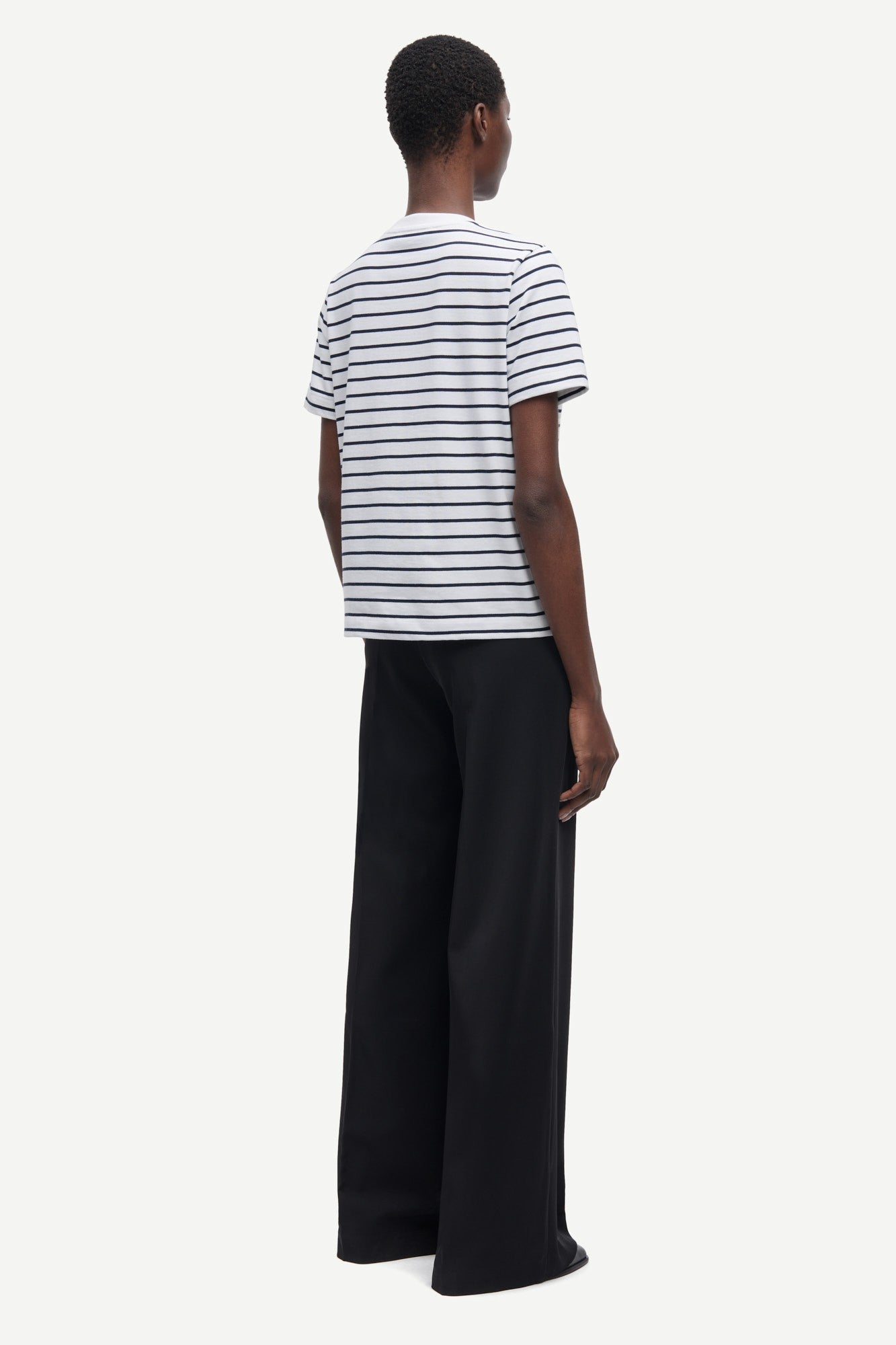 Person wearing a striped shirt and black pants on a white background
