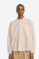 Person wearing a beige shirt against a gray background
