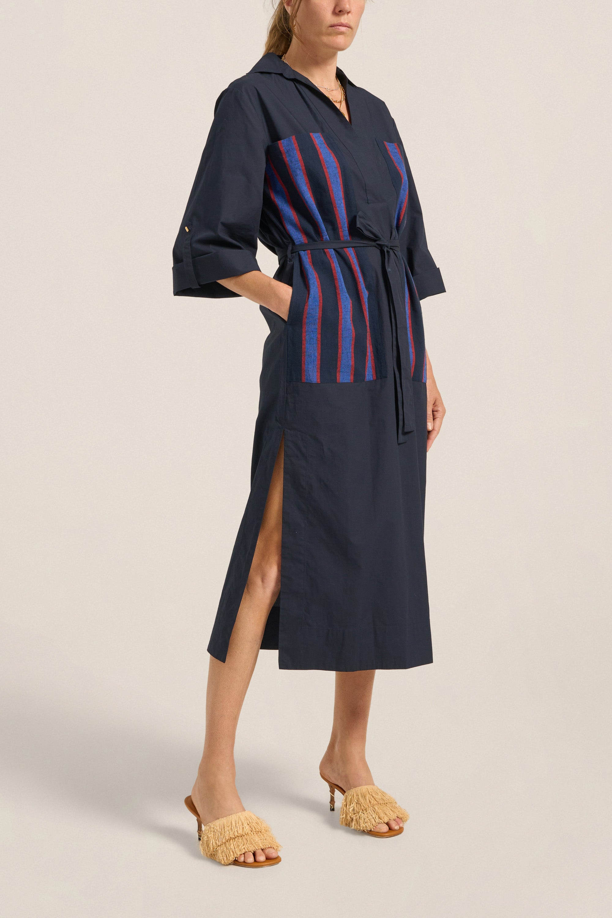 Navy dress with red and blue striped panel worn by a model on a beige background